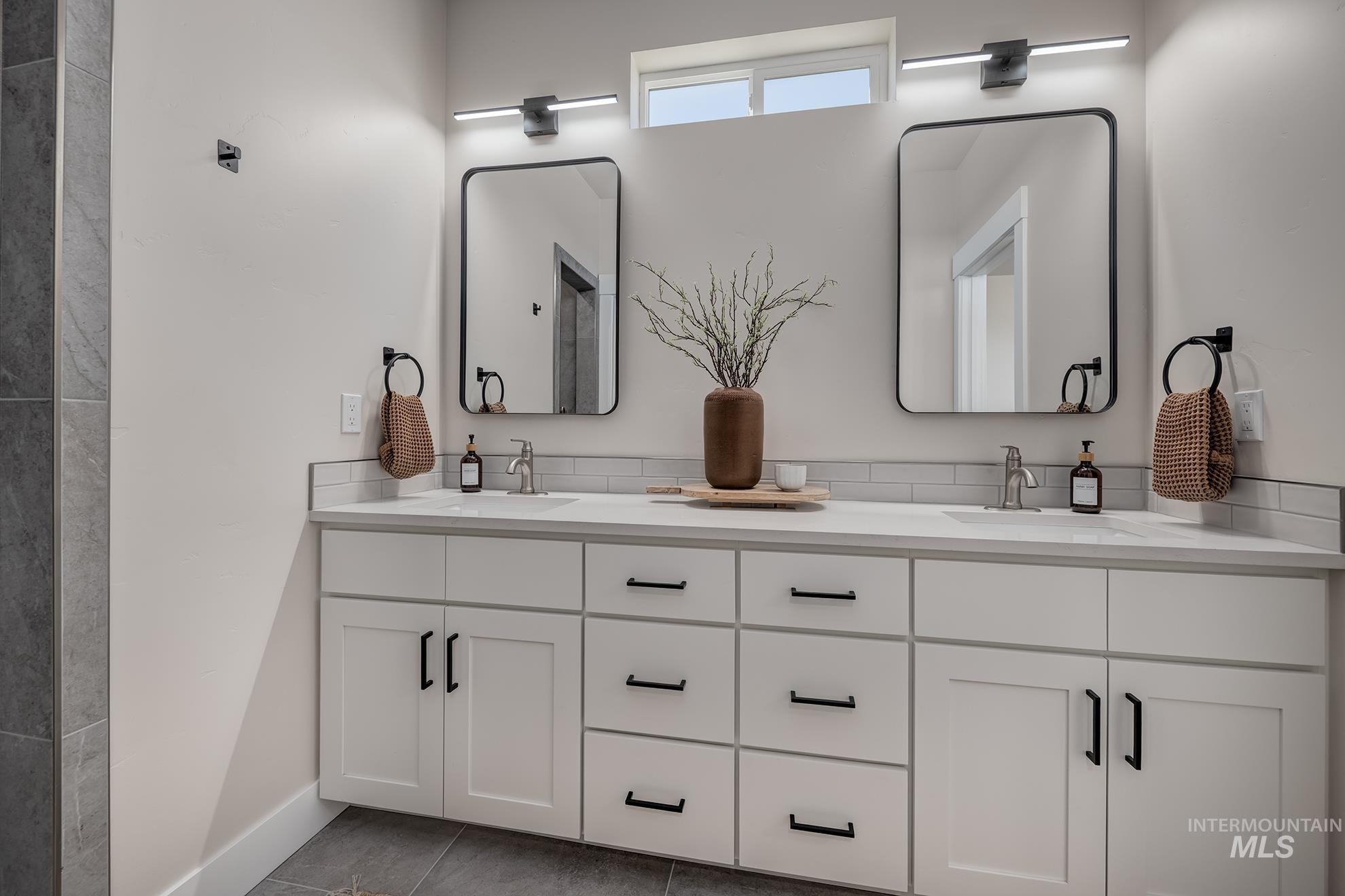 1371 Hansen Road Weiser, ID 83672 - Photo 21 of 44 Dual vanity with white cabinetry, integrated sinks, brushed nickel faucets, and rectangular black-framed mirrors