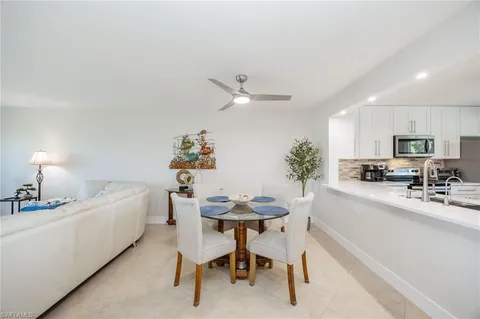 a white kitchen with a sink a stove a dining table and chairs