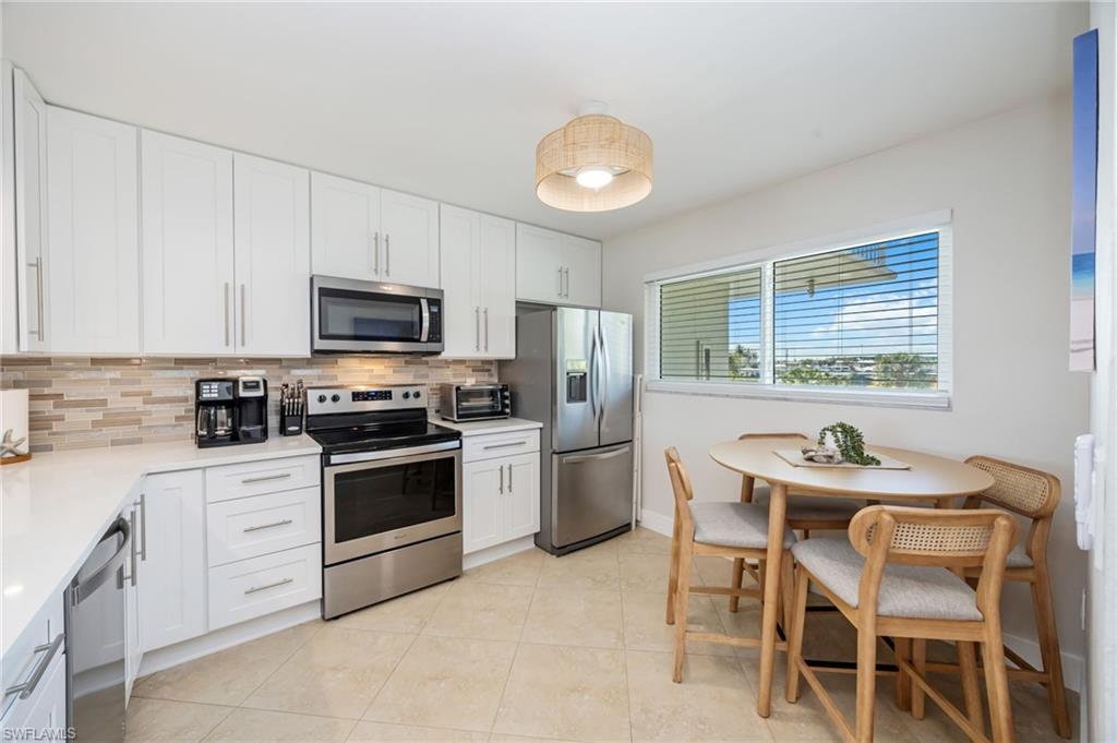 309 Goodlette-Frank Road, Unit A406 Naples, FL 34102 - Photo 5 of 20 a kitchen with a stove a sink dishwasher a dining table and chairs