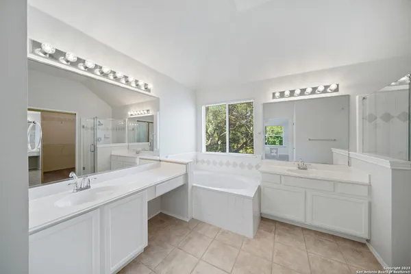 a bathroom with a tub a sink and a large mirror