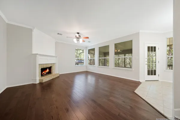 a view of an empty room with wooden floor fireplace and a window