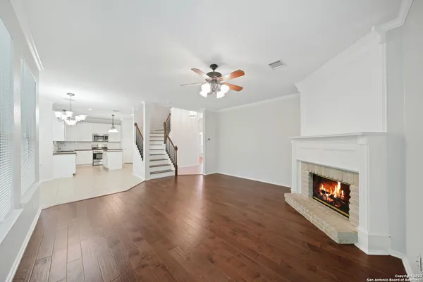 a view of an empty room with wooden floor and a kitchen