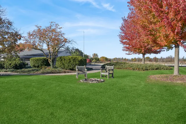 a white bench sitting in the grass near a tree