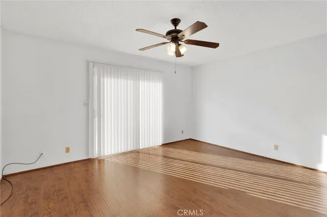 an empty room with wooden floor fan and windows