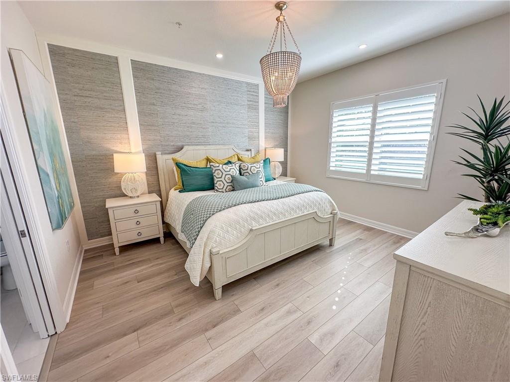 232 Indies Drive East, Unit 201 Naples, FL 34114 - Photo 18 of 49 a bedroom with a bed wooden floor and window