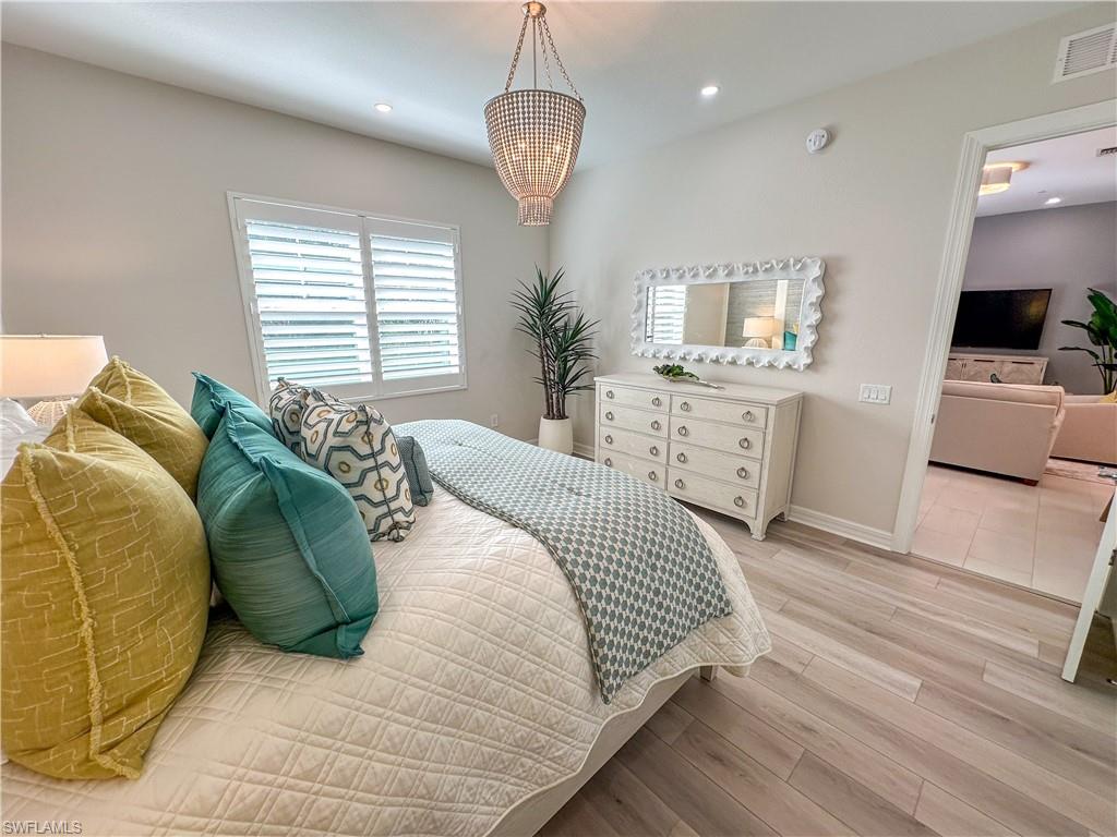 232 Indies Drive East, Unit 201 Naples, FL 34114 - Photo 19 of 49 a bedroom with a bed and a chandelier