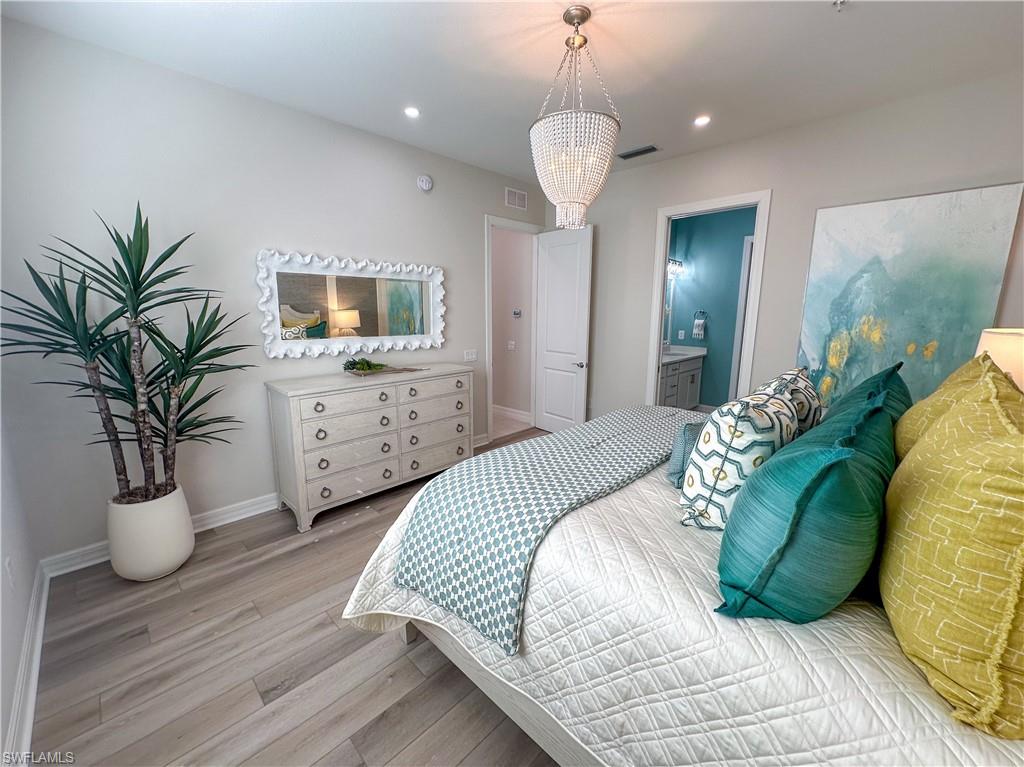 232 Indies Drive East, Unit 201 Naples, FL 34114 - Photo 21 of 49 a bedroom with a large bed and a chandelier