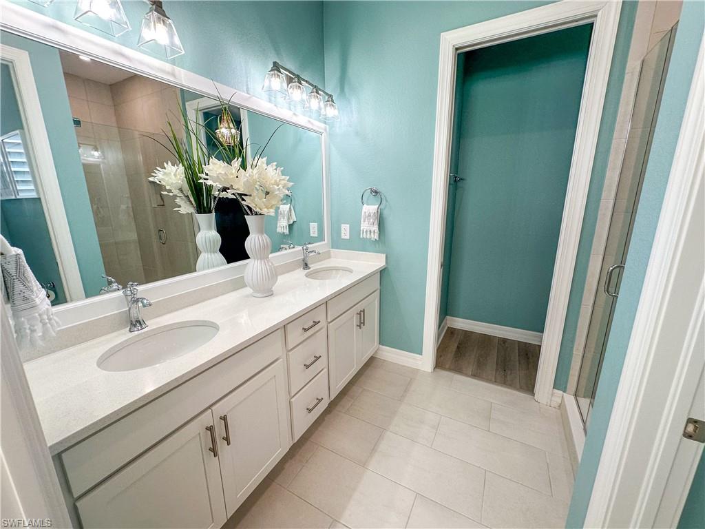 232 Indies Drive East, Unit 201 Naples, FL 34114 - Photo 22 of 49 a spacious bathroom with a double vanity sink and a mirror