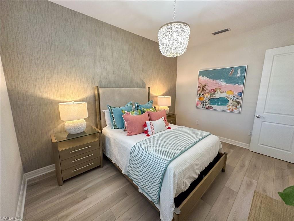 232 Indies Drive East, Unit 201 Naples, FL 34114 - Photo 36 of 49 a bedroom with a bed and a chandelier