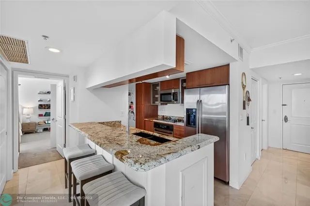 a kitchen with stainless steel appliances granite countertop a sink and a refrigerator