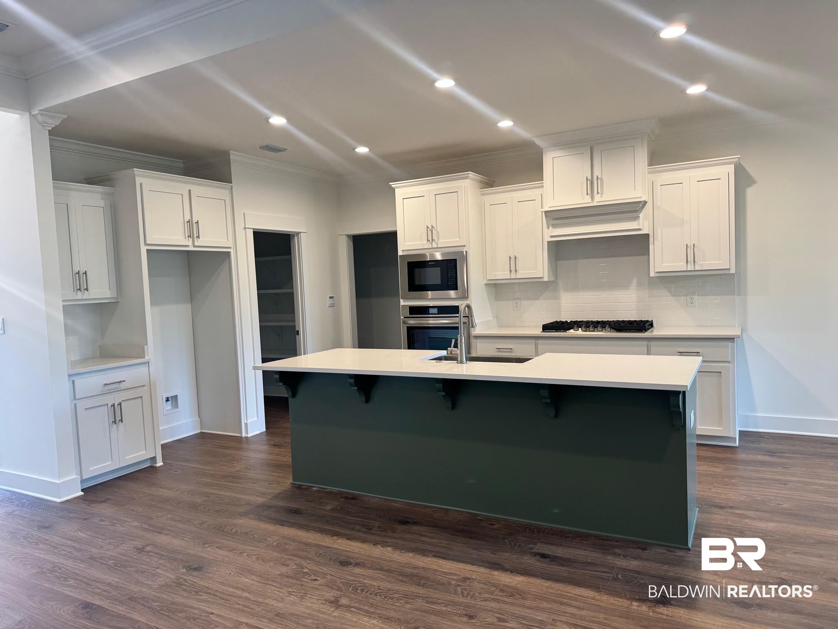 12248 Exbury Way Daphne, AL 36527 - Photo 3 of 63 Kitchen with ornamental molding, a breakfast bar, dark wood-type flooring, stainless steel appliances, and recessed lighting