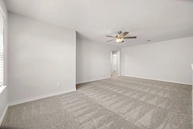 an empty room with chandelier fan and windows