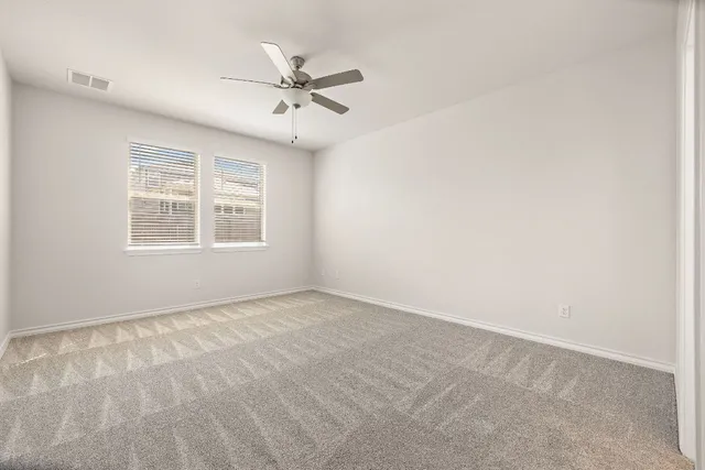 an empty room with a window and a fan