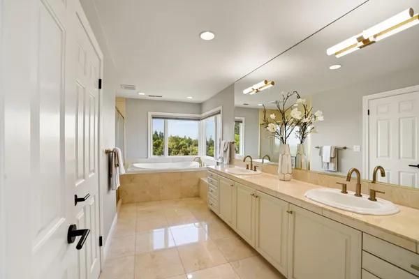 a large white bathroom with a large tub sink and mirror