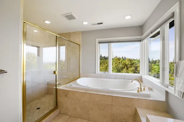 a bathroom with a large tub a shower and view