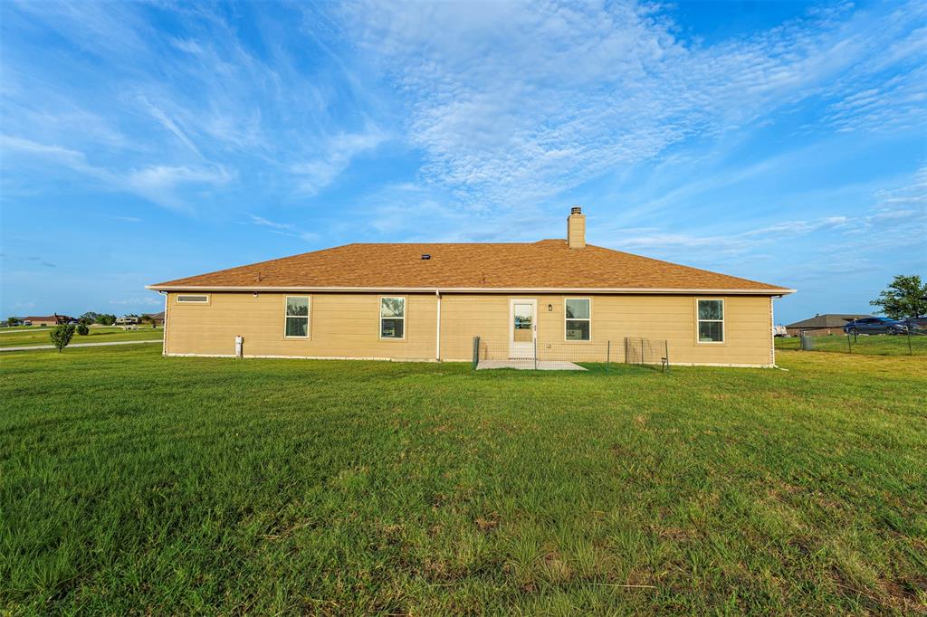 129 Springwood Ranch Loop Springtown, TX 76082 - Photo 24 of 29 Expansive rear yard featuring a concrete patio, exterior lighting, and a single chimney