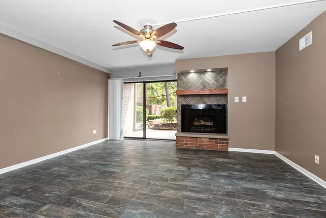 an empty room with wooden floor fireplace and windows