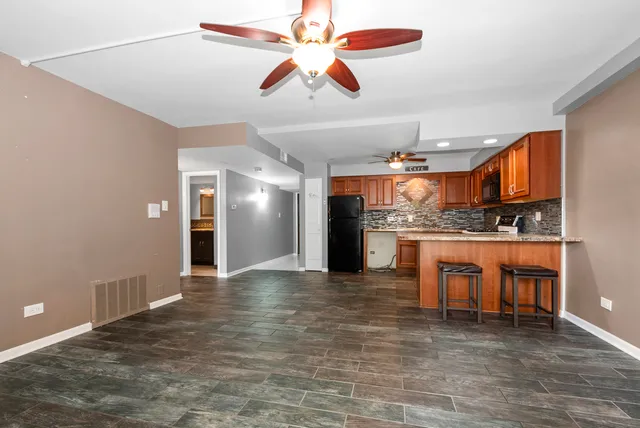 a view of an empty room with kitchen and a window