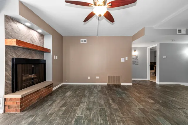 a view of an empty room with wooden floor fireplace and a window