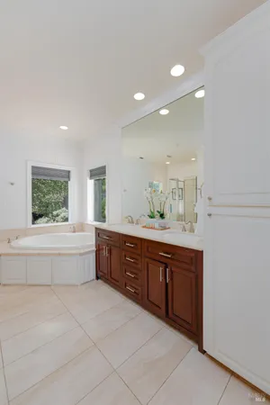 a spacious bathroom with a tub sink and mirror