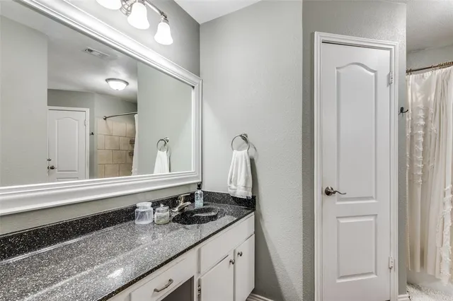 a bathroom with a granite countertop sink and a mirror