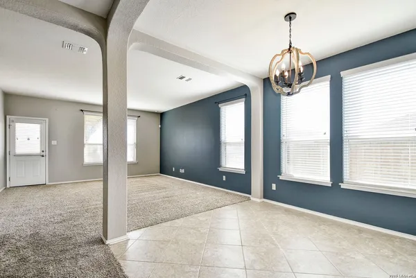 a view of an empty room with a window and chandelier