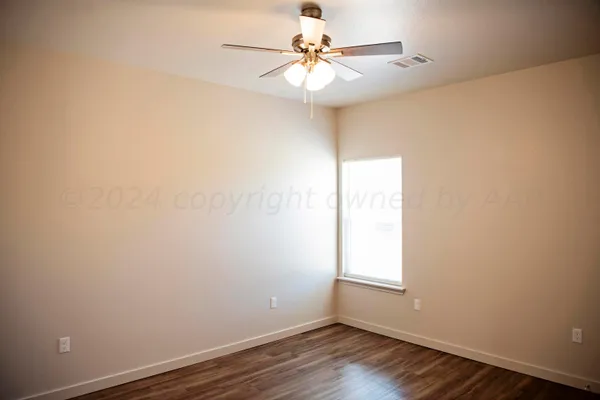an empty room with wooden floor cabinet and windows