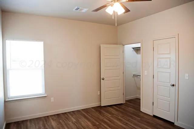 an empty room with wooden floor cabinet and windows
