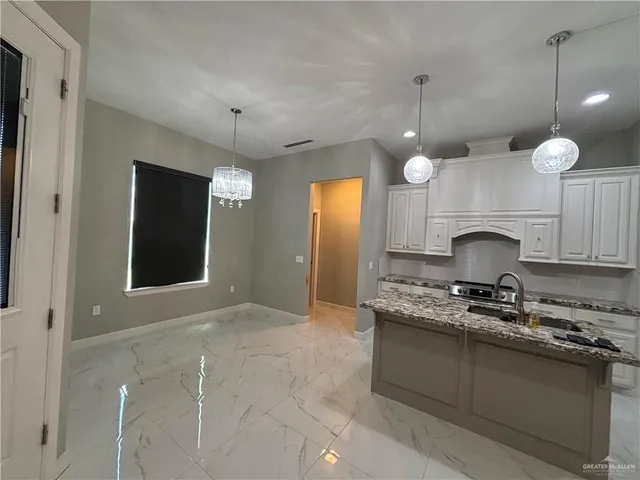 a kitchen with kitchen island granite countertop a stove a sink a counter space and cabinets