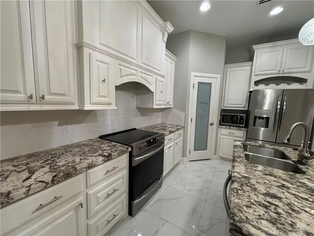 a kitchen with granite countertop a stove sink and cabinets