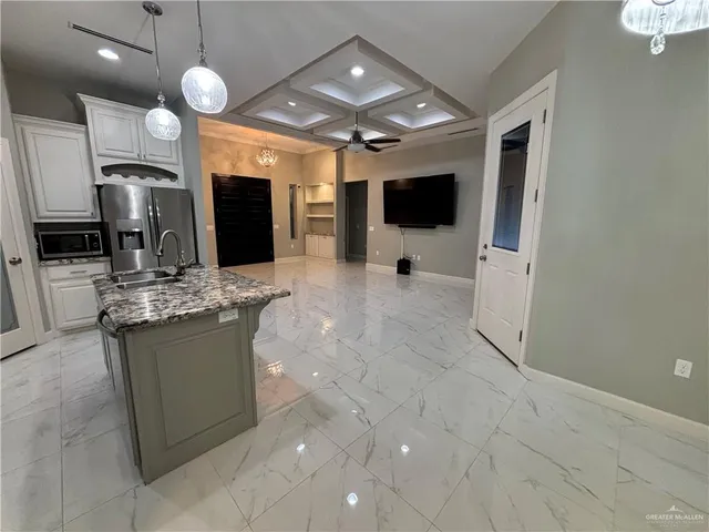 a view of kitchen with stainless steel appliances kitchen island granite countertop a stove top oven a sink and a refrigerator