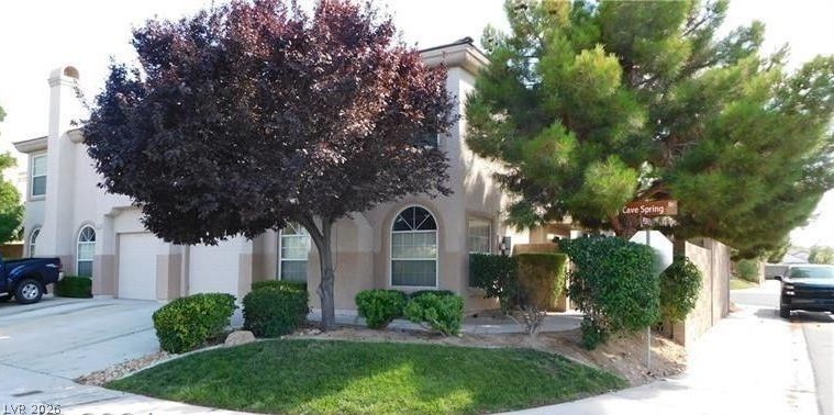 1623 Cave Spring Drive Henderson, NV 89014 - Photo 1 of 16 A cream-colored stucco home features a two-car garage and a neatly maintained front lawn.