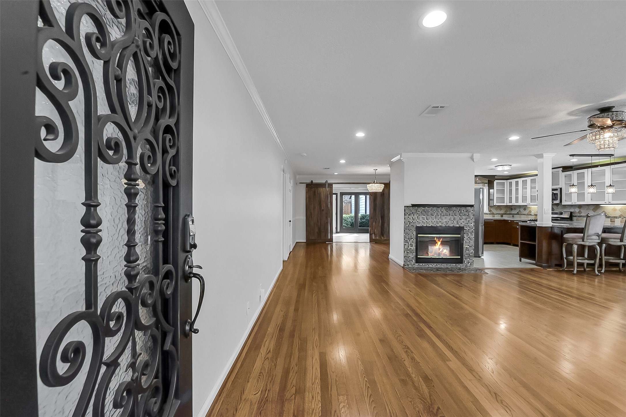 9623 Val Verde Street Houston, TX 77063 - Photo 4 of 26 Welcoming front entry opens to a light-filled living room featuring wood floors, crown molding & a gas log fireplace w/tile surround. Open-concept layout seamlessly connects to the kitchen & dining area — ideal for everyday living & entertaining.