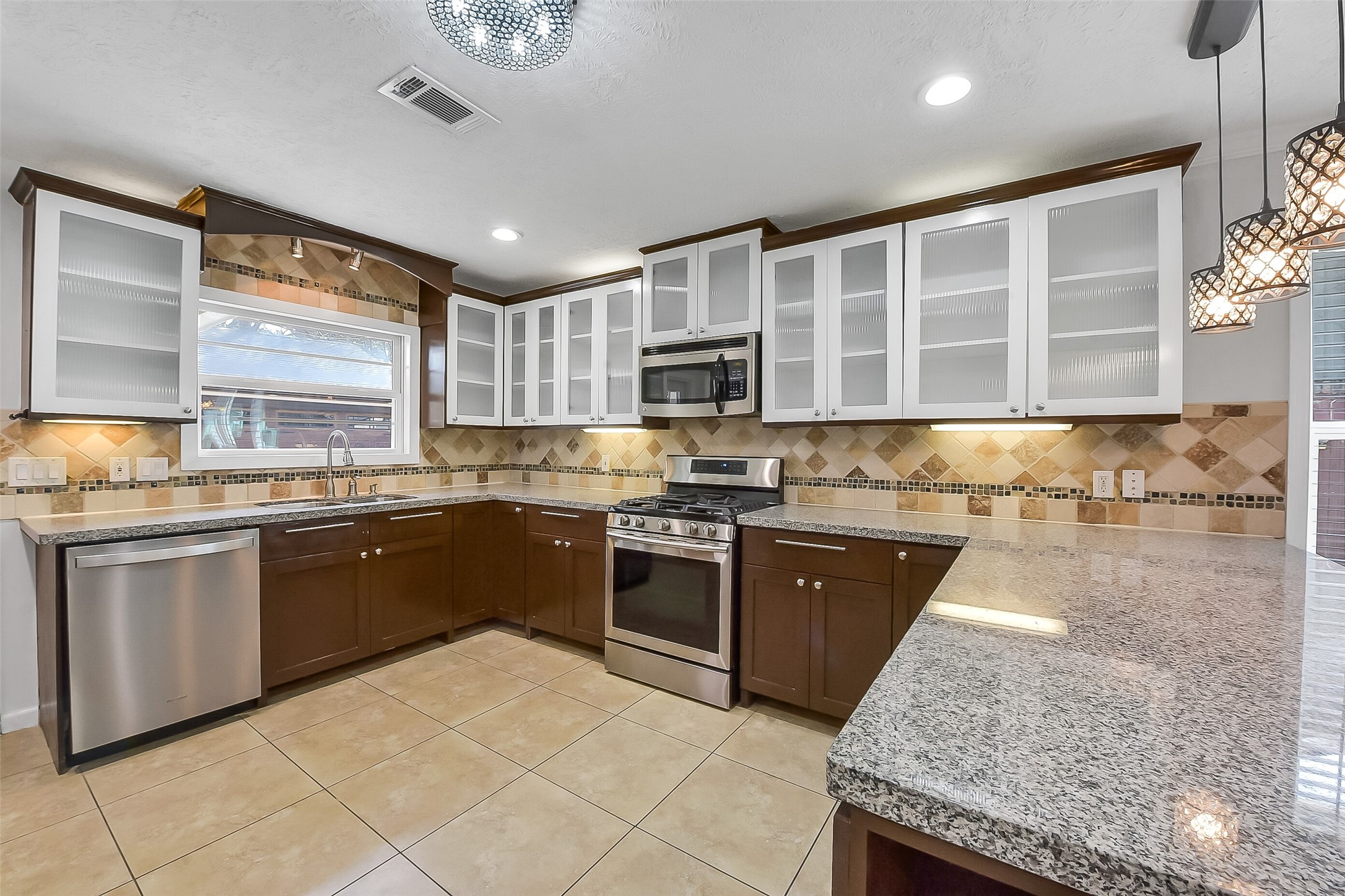 9623 Val Verde Street Houston, TX 77063 - Photo 7 of 26 Well-appointed kitchen featuring granite countertops, stainless steel appliances: refrigerator ('22) & dishwasher, gas range ('19), decorative backsplash, recessed lighting & abundant cabinetry including glass-front display cabinets & soft-close drawers.