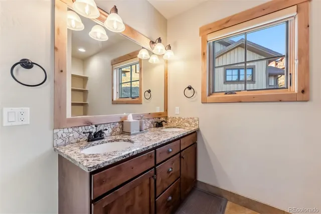 a bathroom with a granite countertop double vanity and a mirror