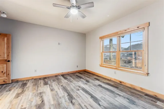 a view of an empty room with a window and wooden floor