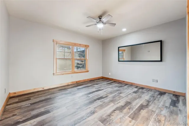 a view of an empty room with window and wooden floor
