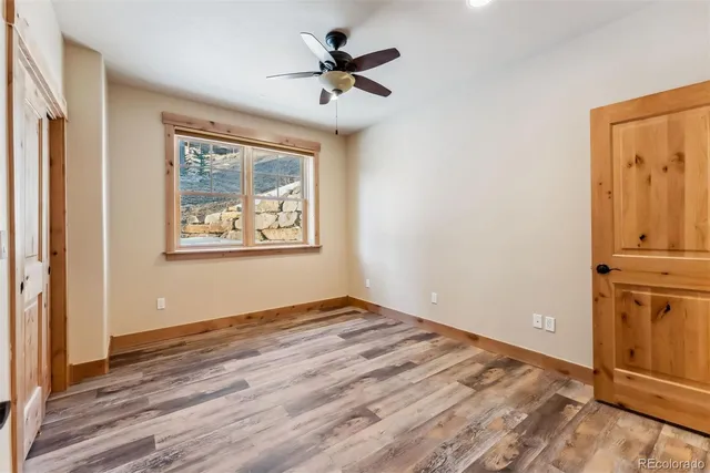 an empty room with wooden floor ceiling fan and windows