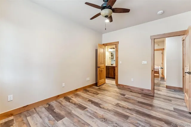 an empty room with wooden floor closet and ceiling fan