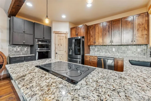 a kitchen with kitchen island granite countertop a stove and a refrigerator
