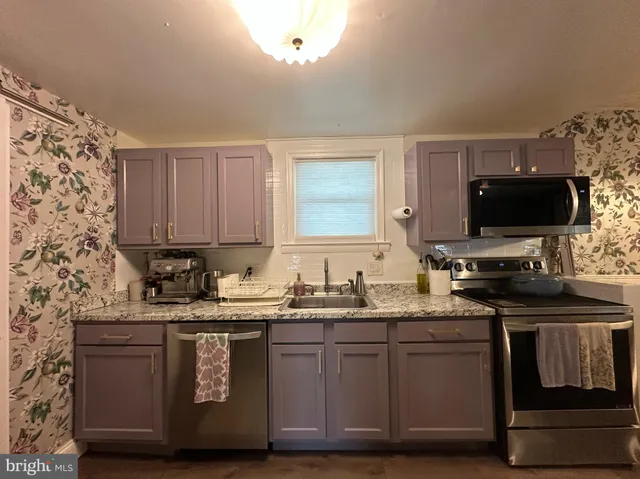 a kitchen with stainless steel appliances granite countertop a sink stove and microwave