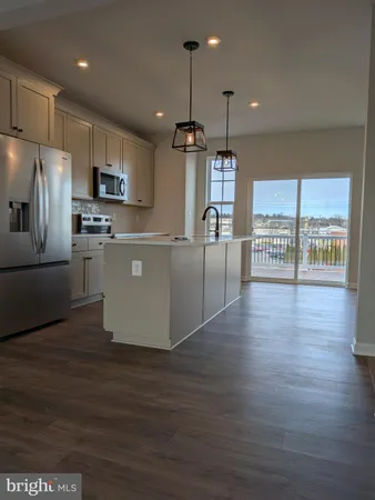 a kitchen with stainless steel appliances granite countertop a refrigerator a sink a stove and a wooden floors