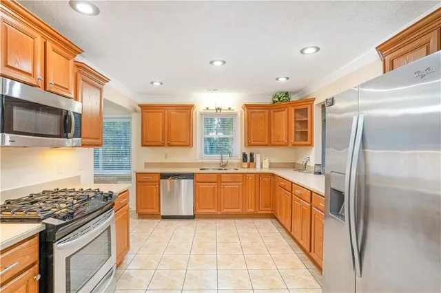 a large kitchen with stainless steel appliances granite countertop a stove top oven a sink dishwasher a refrigerator and cabinets with wooden floor