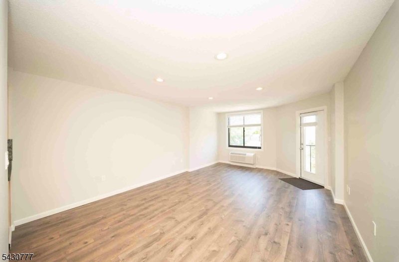 115 Polifly Road, Unit 5D Hackensack, NJ 07601 - Photo 2 of 10 an empty room with wooden floor and windows