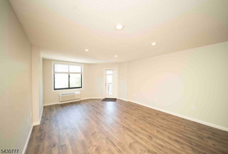 115 Polifly Road, Unit 5D Hackensack, NJ 07601 - Photo 3 of 10 an empty room with wooden floor and windows