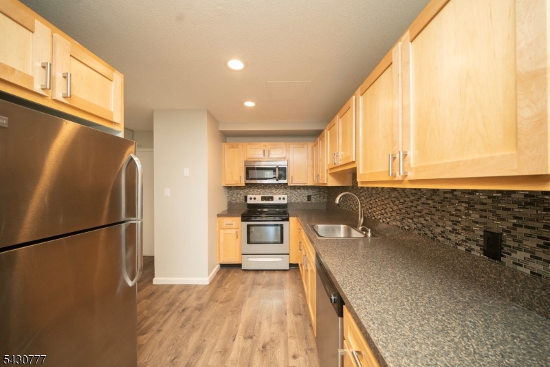 115 Polifly Road, Unit 5D Hackensack, NJ 07601 - Photo 5 of 10 a kitchen with stainless steel appliances granite countertop a refrigerator a sink dishwasher a stove with wooden cabinets