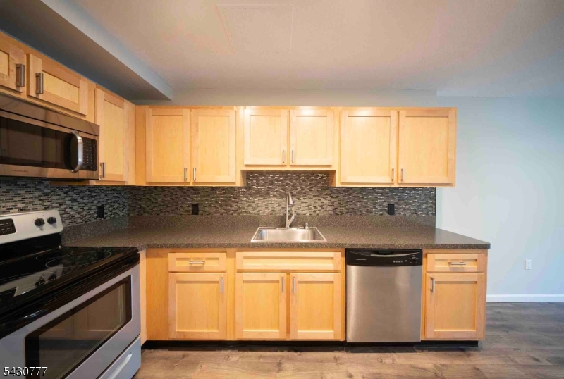 115 Polifly Road, Unit 5D Hackensack, NJ 07601 - Photo 6 of 10 a kitchen with stainless steel appliances granite countertop a stove a sink and a microwave