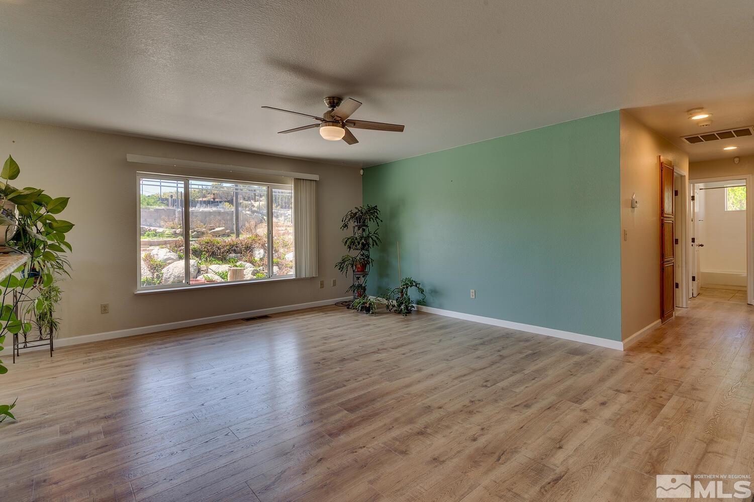 16015 Rocky Vista Road Reno, NV 89521 - Photo 6 of 20 an empty room with wooden floor chandelier and windows