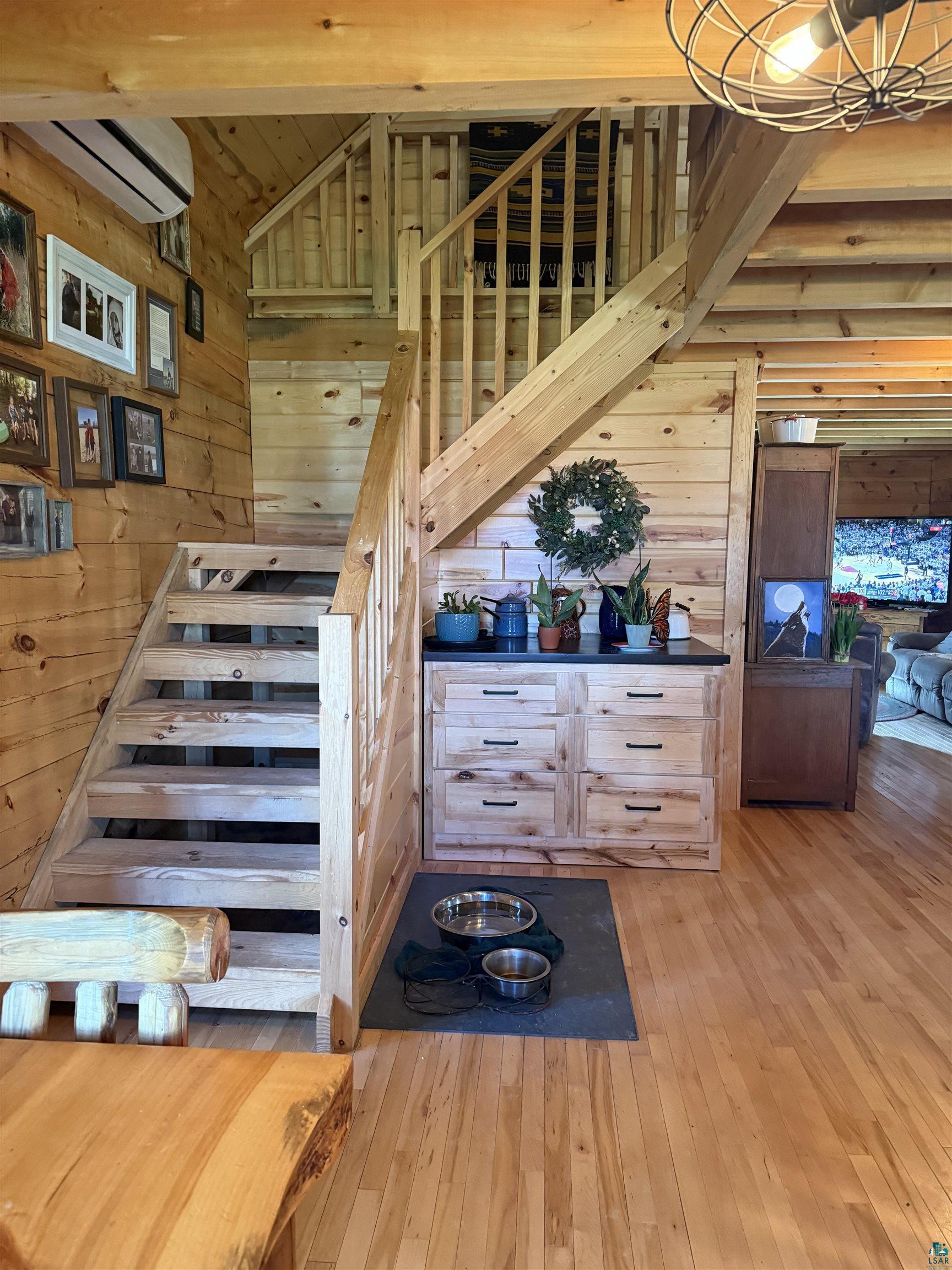 37590 Degerstrom Road Askov, MN 55704 - Photo 12 of 53 Natural wood staircase with matching railing, wood-finish flooring, built-in cabinetry with dark countertops, and exposed beam ceiling