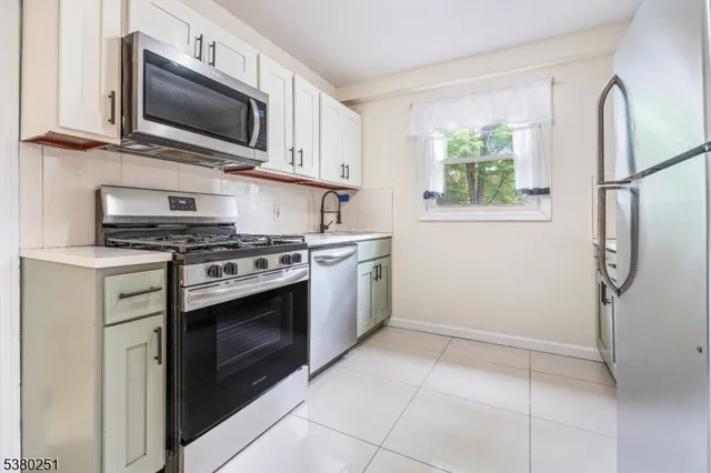 a kitchen with cabinets stainless steel appliances and a window